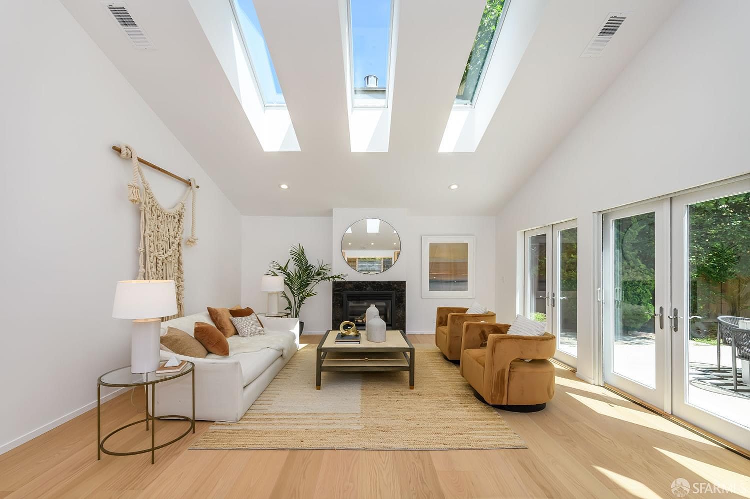 Living room with three skylights tracing the vaulted ceiling, white sofa, terracotta accent chairs